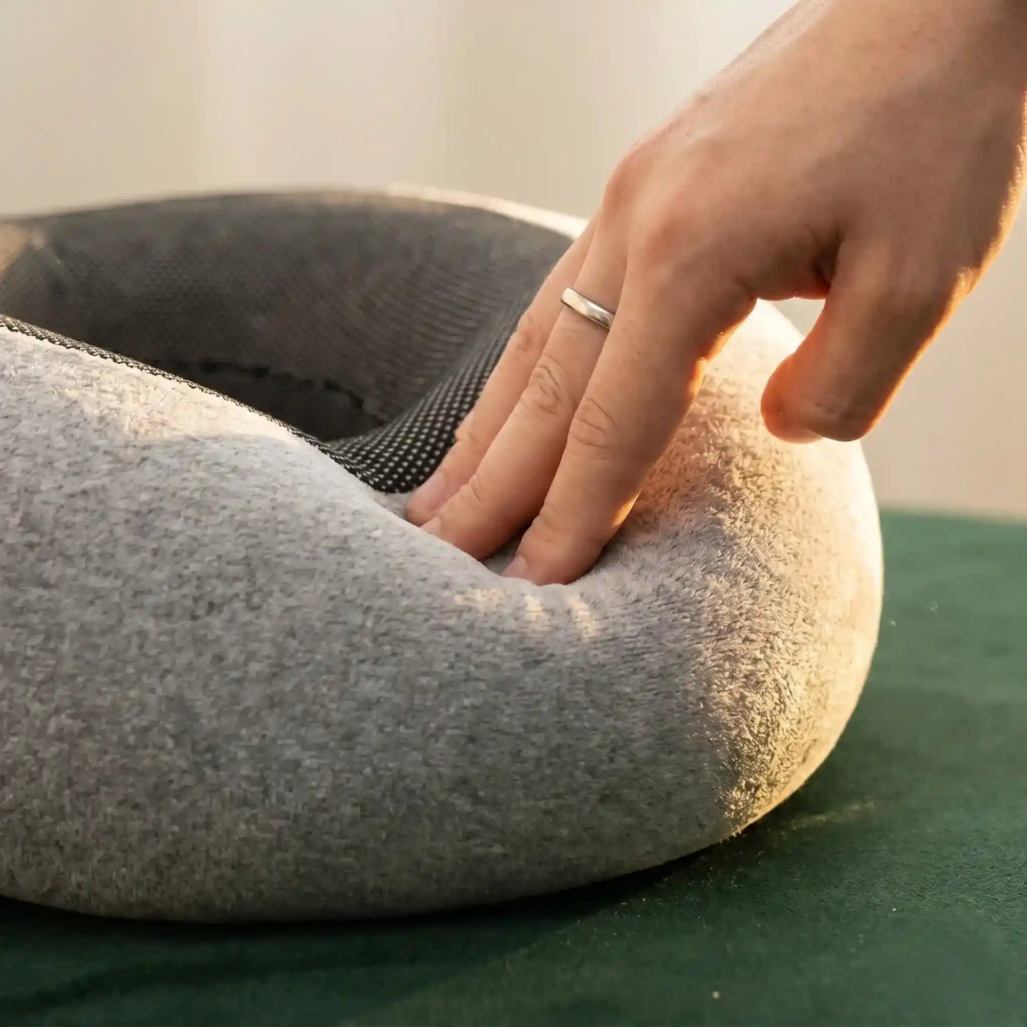 Person using a gray donut-shaped cushion on a green surface with a blurred background