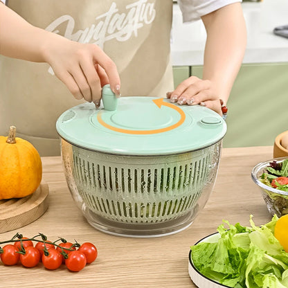 Person using a salad spinner with vegetables on a table