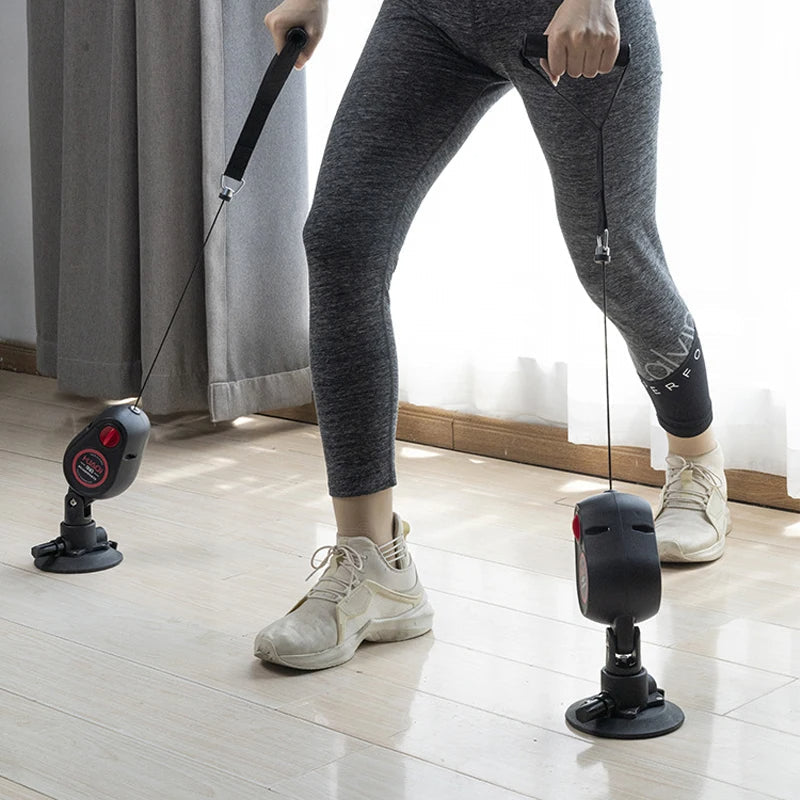 Person using a resistance band exercise device on a wooden floor.