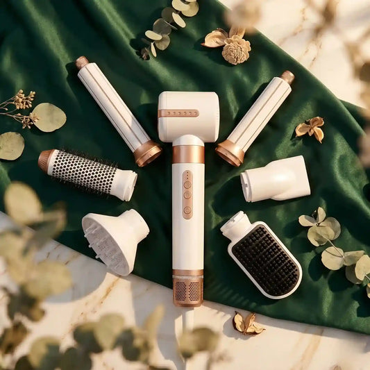 Set of hair styling tools on a green fabric background with leaves.