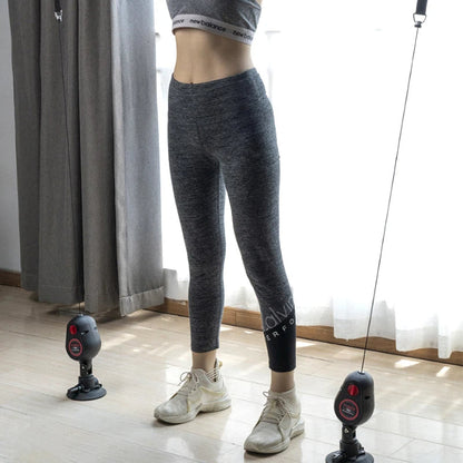 Person wearing gray leggings and white sneakers in a room with curtains and exercise equipment.