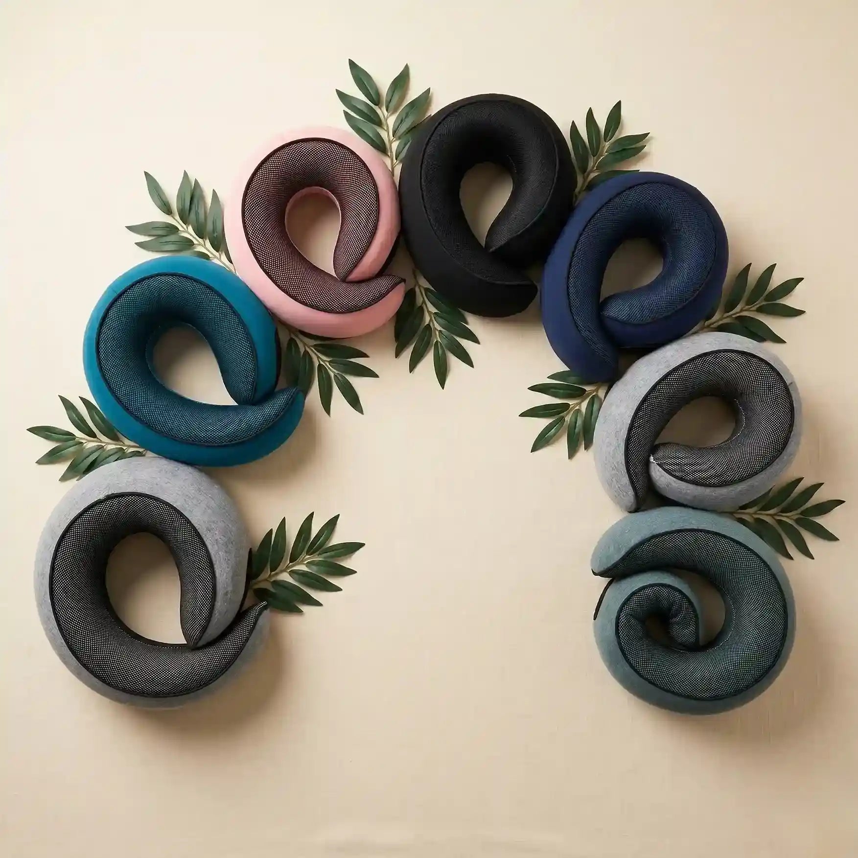 Set of colorful neck pillows arranged in a circular pattern on a beige background with green leaves.